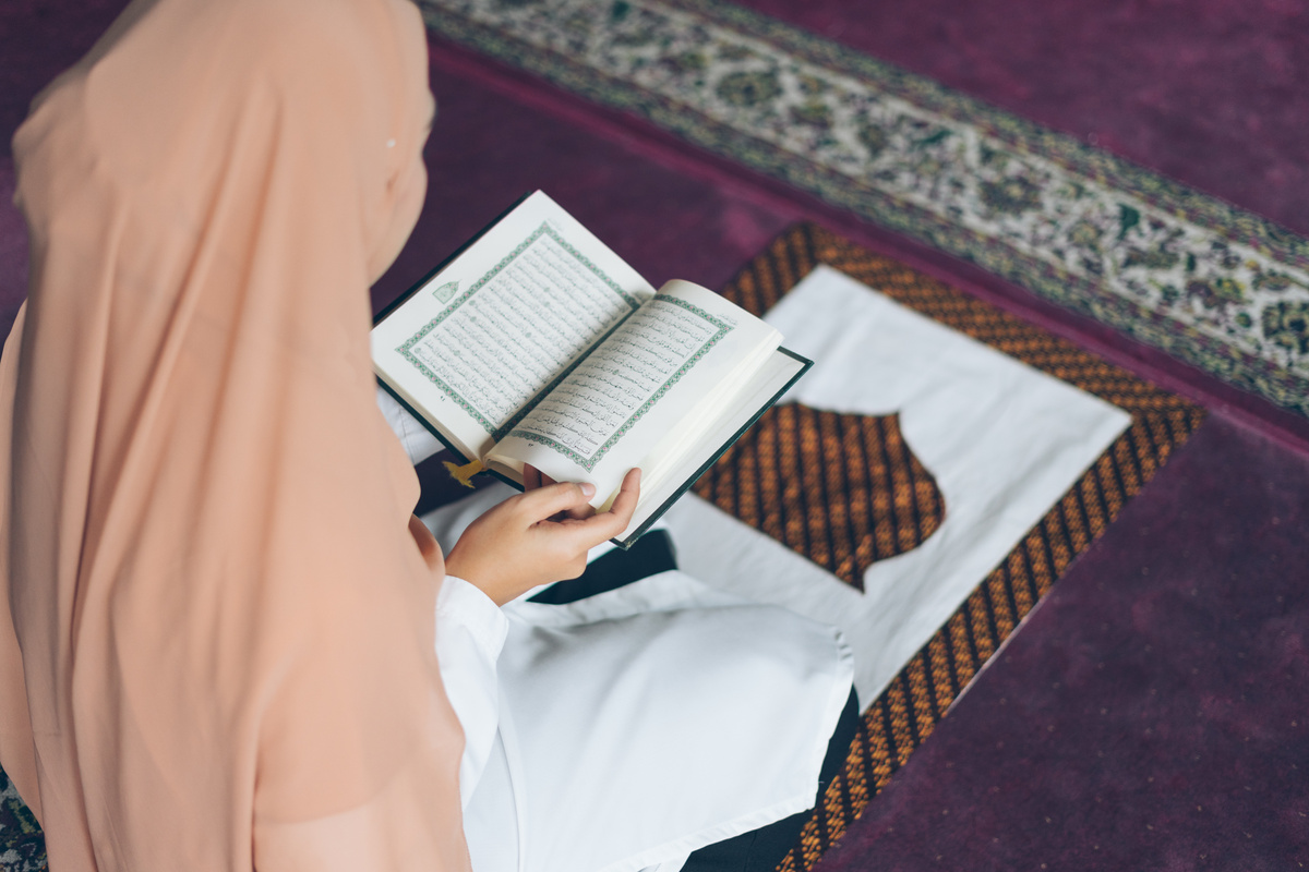 Woman in Hijab Reading a Quran Indoors
